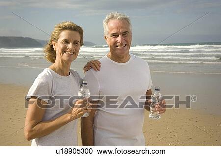 Couple drinking water on a beach View Large Photo Image Stock Image - Couple drinking water on a beach. Fotosearch