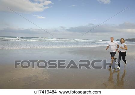 Picture - Couple running on a beach. Fotosearch