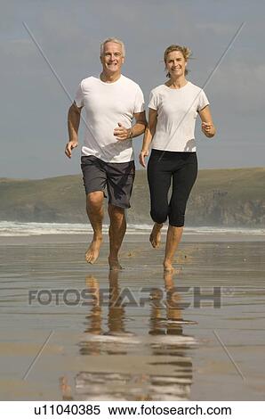 Couple running on a beach View Large Photo Image Stock Photography - Couple running on a beach. Fotosearch