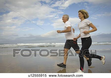 Couple running on a beach View Large Photo Image Stock Photography - Couple running on a beach. Fotosearch