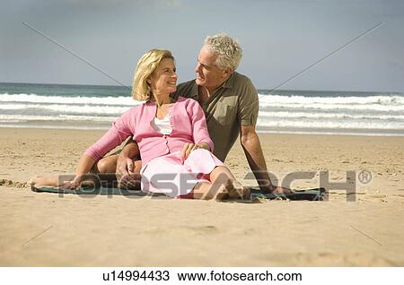 Couple sat on a beach View Large Photo Image Stock Image - Couple sat on a beach. Fotosearch