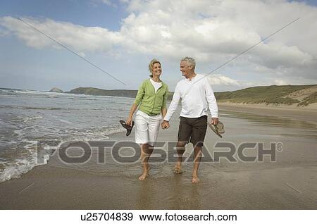 Couple walking hand in hand on a beach View Large Photo Image Stock Photo - Couple walking hand in hand on a beach. Fotosearch