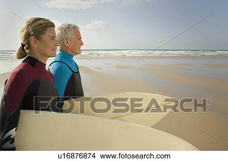 Couple with surfboards on a beach View Large Photo Image Picture - Couple with surfboards on a beach. Fotosearch
