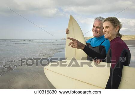 Couple with surfboards on a beach View Large Photo Image Stock Image - Couple with surfboards on a beach. Fotosearch