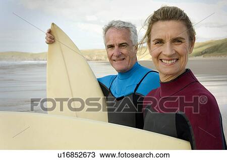 Couple with surfboards on a beach View Large Photo Image Stock Image - Couple with surfboards on a beach. Fotosearch