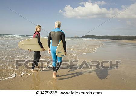 Stock Photograph - Couple with surfboards on a beach. Fotosearch