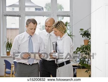 Stock Image - Coworkers looking over paper work. Fotosearch