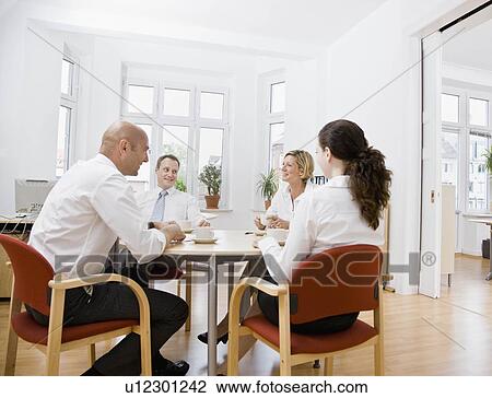Stock Image - Coworkers talking over a meeting. Fotosearch
