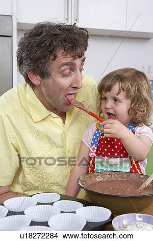 Picture - Daughter is feeding father with batter. Fotosearch