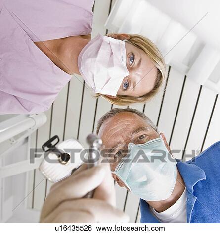 Stock Photograph - Dentist and assistant using tools. Fotosearch