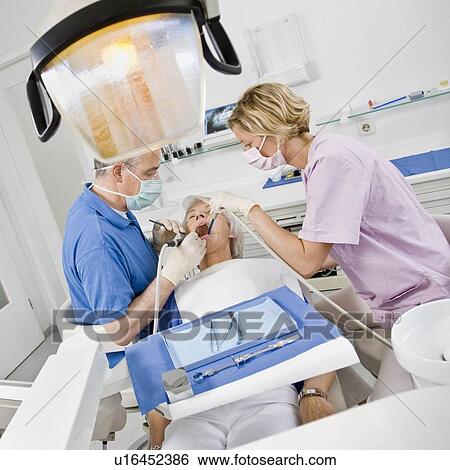 Stock Photograph - Dentist and assistant working on patient. Fotosearch