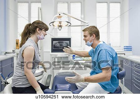 Stock Image - Dentist talking with assistant. Fotosearch