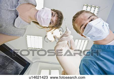 Stock Image - Dentist with dental tools and assistant. Fotosearch