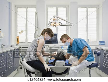 Picture - Dentist with patient and assistant. Fotosearch