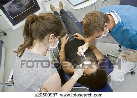 Stock Photo - Dentist with patient and assistant. Fotosearch