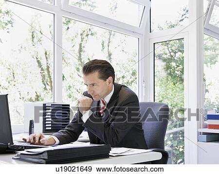 Stock Photo - Determined man looking at laptop. Fotosearch