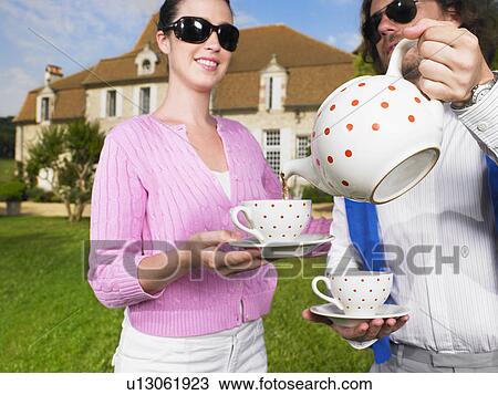 Stock Image - Drinking tea in front of country home. Fotosearch