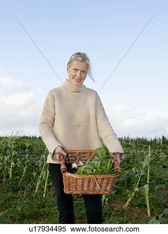 Stock Photography - farm worker carries basket of veg. Fotosearch