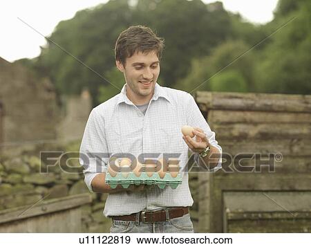 Stock Photo - Farmer Looking At Tray Of Eggs. Fotosearch