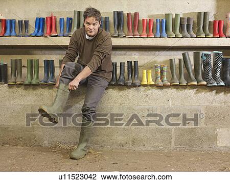 Stock Image - Farmer Putting On Wellington Boots. Fotosearch