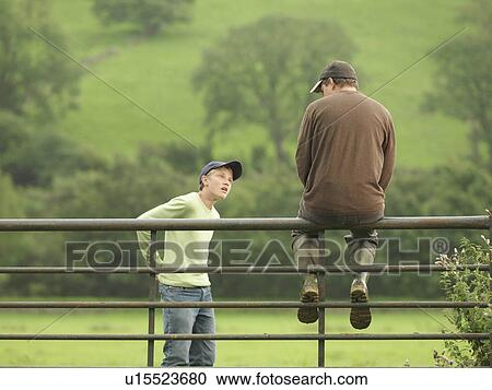 Stock Image - Farmer Talking To Son On Gate. Fotosearch