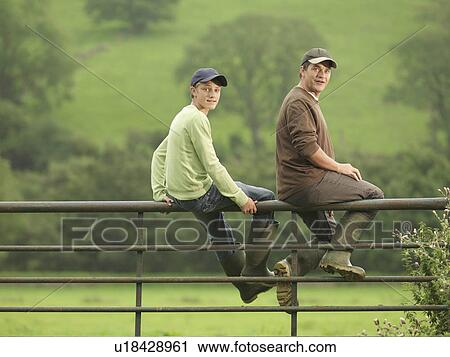 Stock Image - Farmer Talking To Son On Gate. Fotosearch