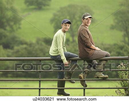 Stock Image - Farmer Talking To Son On Gate. Fotosearch