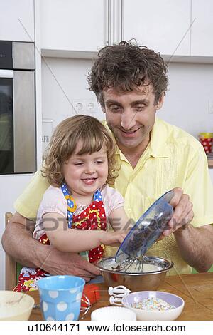 Stock Image - Father and daughter, preparing dessert. Fotosearch