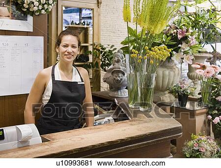 Stock Image - Female clerk in a flower shop. Fotosearch