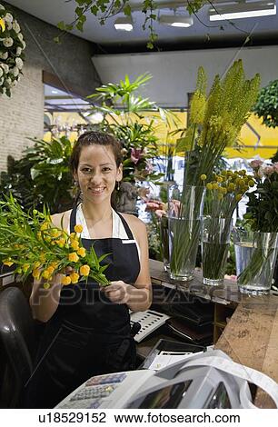 Stock Image - Female clerk in a flower shop. Fotosearch