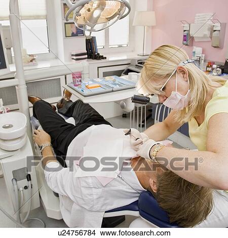 Picture - Female dentist working on a male patient. Fotosearch