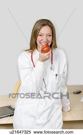 Stock Photography - Female doctor eating apple. Fotosearch