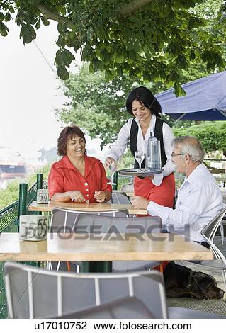Stock Image - Female waitress bringing drinks. Fotosearch