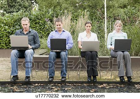 Stock Image - Four business people working outside.. Fotosearch