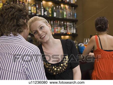 Stock Image - Friends sitting at bar drinking. Fotosearch