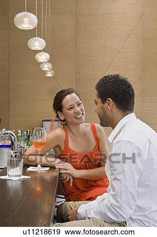 Stock Photo - Friends sitting at bar drinking. Fotosearch