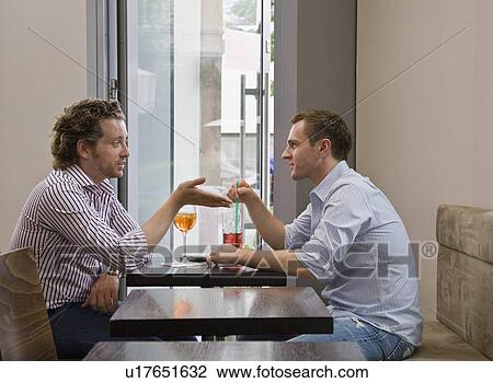 Friends sitting at table talking View Large Photo Image Stock Image - Friends sitting at table talking. Fotosearch