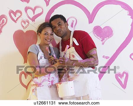Stock Image - Girl and man in front of pink hearts.. Fotosearch