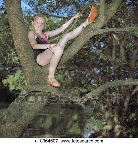 Stock Photo - Girl perched in a tree over a river. Fotosearch
