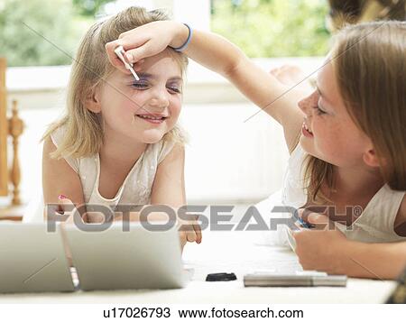 Stock Image - Girl putting eye shadow on a friend. Fotosearch