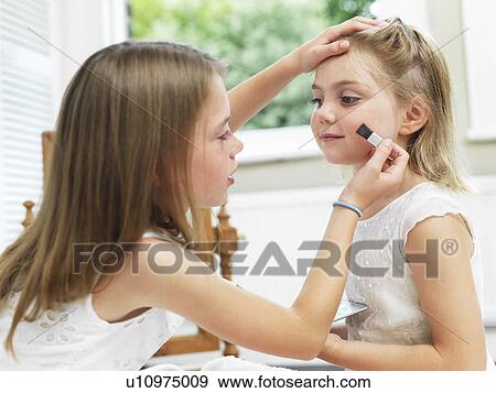 Stock Photo - Girl putting make-up on friend. Fotosearch