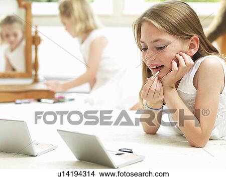 Picture - Girl putting on make-up (lip stick). Fotosearch
