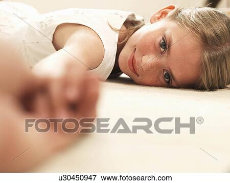 Stock Photo - Girl smiling, resting head on floor. Fotosearch