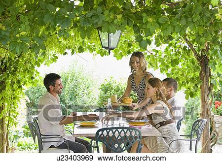 Stock Photo - Group enjoying meal in garden. Fotosearch