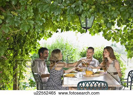 Stock Photography - Group enjoying meal in garden. Fotosearch