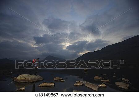 Hiker standing on rocks in a lake. View Large Photo Image Stock Photo - Hiker standing on rocks in a lake.. Fotosearch