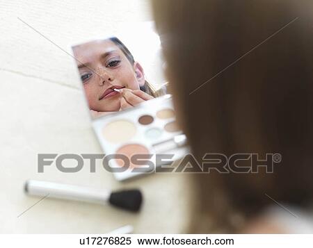 Stock Photography - Looking into mirror, putting on lipstick. Fotosearch
