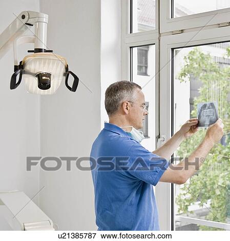 Stock Photo - Male dentist looking at x-rays. Fotosearch