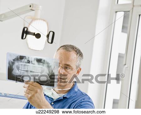 Stock Photo - Male dentist looking at x-rays. Fotosearch