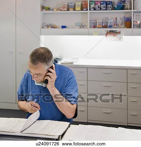 Male dentist talking on a phone View Large Photo Image Stock Photograph - Male dentist talking on a phone. Fotosearch